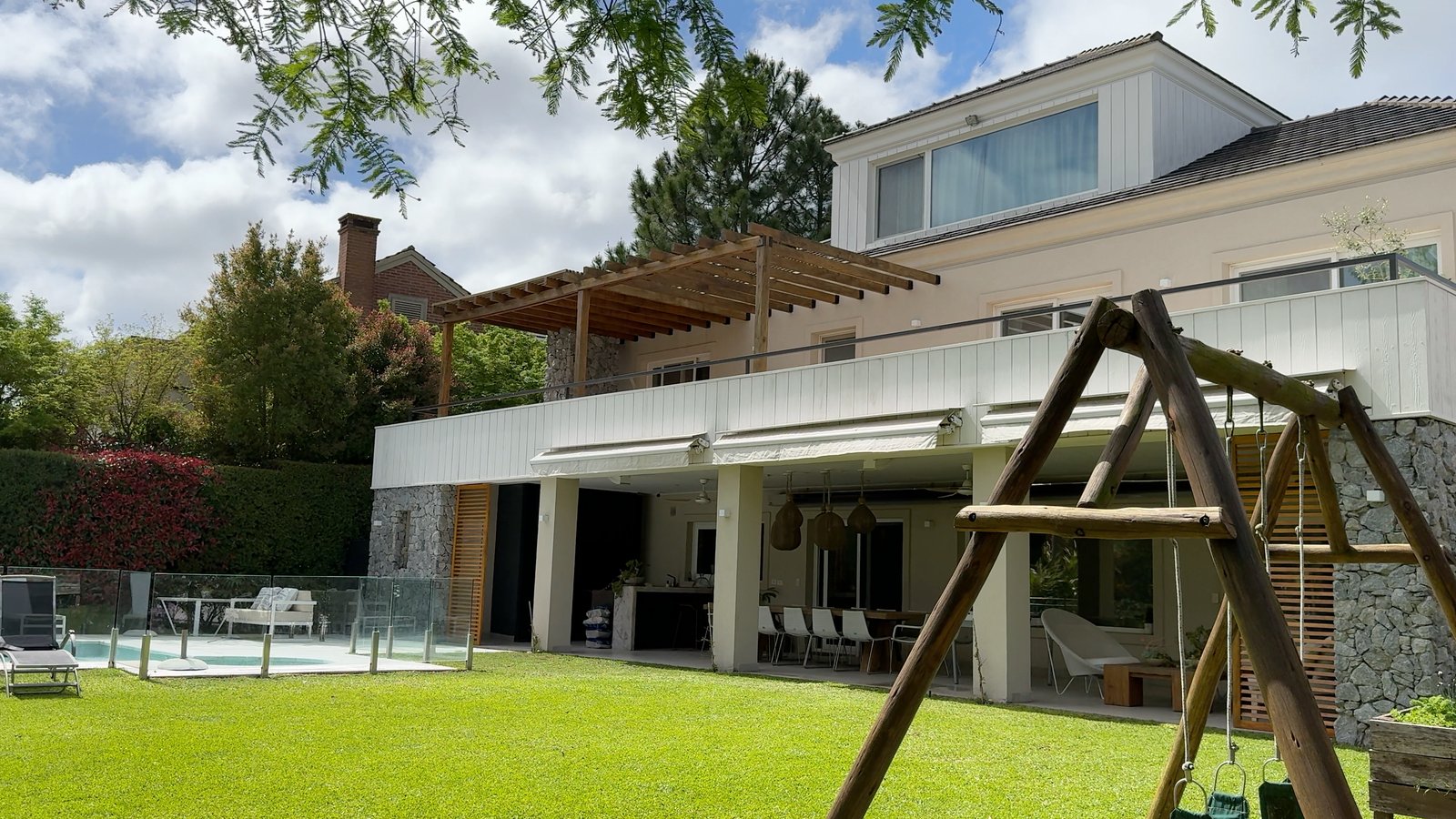 Fachada moderna con piscina, césped y pérgola — proyecto CASA CM, por Hermann Arquitectos, en Los Castores